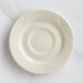 An Acopa Swell ivory stoneware saucer with an embossed circular pattern.