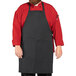 A man wearing a Uncommon Chef black pinstripe butcher apron over a red shirt.