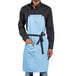 A man wearing a blue Uncommon Chef bib apron with black webbing.
