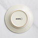 An ivory stoneware plate with a circular embossed rim and black text that says "Acopa" on it.