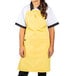 A woman wearing a yellow Uncommon Chef apron with black pants.