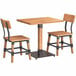 A Lancaster Table & Seating live edge wood table with two wooden chairs with black metal frames.
