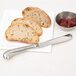 A Vollrath stainless steel butter knife on a plate with two slices of bread and a bowl of jam.
