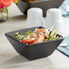 An Acopa matte black stoneware bowl filled with shrimp and vegetables on a table.