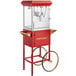A red Carnival King popcorn machine with a gold rim on a cart with wheels.