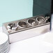 A Steril-Sil stainless steel countertop flatware organizer with 4 cylinders holding spoons and forks.