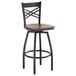 A Lancaster Table & Seating black and wood swivel bar stool with a cross back and wooden seat.