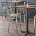 A Lancaster Table & Seating cross back bar stool with a vintage wood seat on a table in a restaurant.