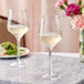 Two Acopa Silhouette wine glasses on a marble table with flowers.
