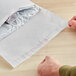 A person's hands opening a Lavex insulated white cotton-based mailer.