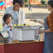 A woman and child at a Carnival King Funnel Cake stand.