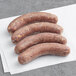 Three Kinikin Processing Rocky Mountain Jalapeno and Cheddar Elk Bratwurst sausages on a white napkin.