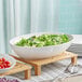 A Tablecraft Sierra white melamine bowl filled with salad on a table.