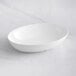 A white oval Tablecraft Sierra melamine bowl on a white surface.