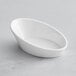 A close up of a white oval shaped Tablecraft mini melamine bowl.
