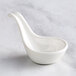 A white bowl with a long handle and a white spoon on top.