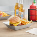 A Tablecraft stainless steel rectangular serving basket with a cheeseburger and fries.
