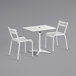 A white Lancaster Table & Seating outdoor table with umbrella hole and two side chairs.