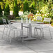 A Lancaster Table & Seating outdoor table with chairs on a patio with a white umbrella.