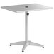 A white aluminum Lancaster Table & Seating outdoor table with a black umbrella on it.