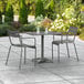 A Lancaster Table & Seating matte gray aluminum table with chairs on an outdoor patio.