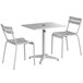 A white Lancaster Table & Seating outdoor table with umbrella hole and two chairs.
