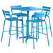 A blue table with a black umbrella hole and four barstools with blue seats on an outdoor patio.