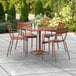 A Lancaster Table & Seating brown powder-coated aluminum outdoor dining table with chairs on an outdoor patio.
