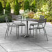 A Lancaster Table & Seating matte gray aluminum outdoor dining table with chairs and an umbrella on a patio.