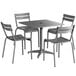 A Lancaster Table & Seating matte gray metal outdoor dining set with four chairs on a table with an umbrella hole.