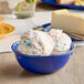 A blue melamine bowl filled with ice cream and sprinkles.