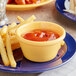 A plate of french fries with a bowl of ketchup on a table.