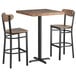 A Lancaster Table & Seating vintage butcher block bar height table with wooden top and metal legs with 2 wooden boomerang chairs.