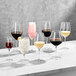 A group of Della Luce Maia burgundy wine glasses on a marble table.