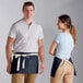 A man and woman wearing Choice navy blue waist aprons with natural webbing.