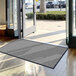 A Lavex gray antimicrobial entrance mat in front of a large glass door.