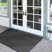 A black Lavex Chevron Rib entrance mat on a double door with glass panes.