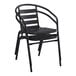 A black metal Lancaster Table & Seating outdoor arm chair with a curved back.