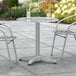 A Lancaster Table & Seating chrome round outdoor table set with two drinks on it.