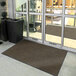 A brown Lavex indoor entrance mat placed in front of a glass door.