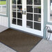 A Lavex brown chevron patterned indoor entrance mat in front of double doors with glass panes.