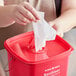 A woman using a tissue to clean a red Noble Products King-Pail lid.