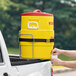 A man loading a yellow Igloo 10 gallon insulated beverage dispenser onto a truck.