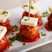 A close up of meatballs with Aged Piccante Provolone cheese and tomato sauce on a white plate.