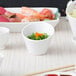 A close up of 10 Strawberry Street Whittier white porcelain tall slant bowl filled with food on a table.