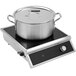 A stainless steel pot with a lid on a Vollrath countertop induction range.