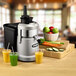 A Waring juice extractor juicing a variety of fruits and vegetables on a counter.