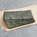 Half sheet of blue seaweed sushi nori on a piece of paper.