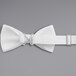 A white poly-satin bow tie with adjustable metal clips.