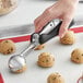A hand using an OXO Good Grips ice cream scoop to dish out cookies.